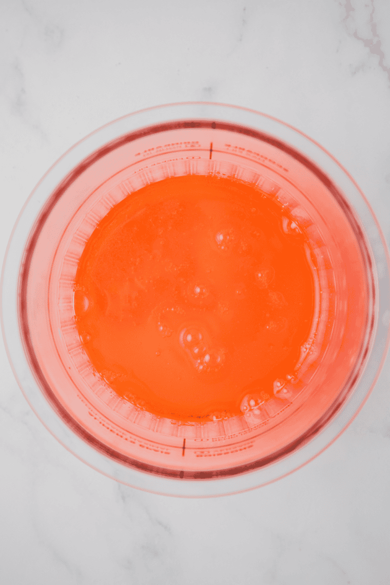 Orange syrup, cream, sugar, water, and vanilla mixed in bowl.