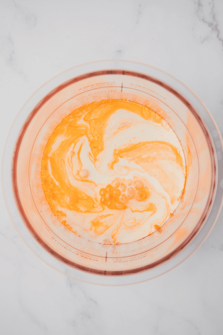 Orange creamsicle mixture poured into Ninja Creami pint container.