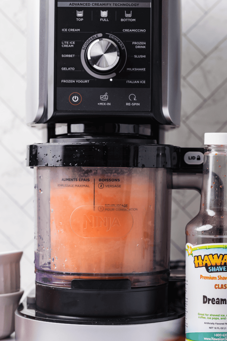 Frozen orange mixture spinning in Ninja Creami on sorbet setting.