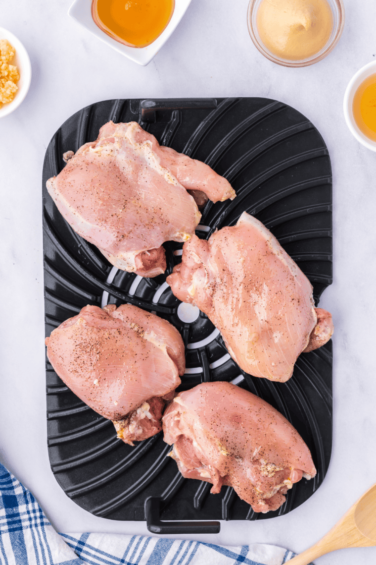 Chicken thighs grilling in the Ninja Foodi, turning golden brown.