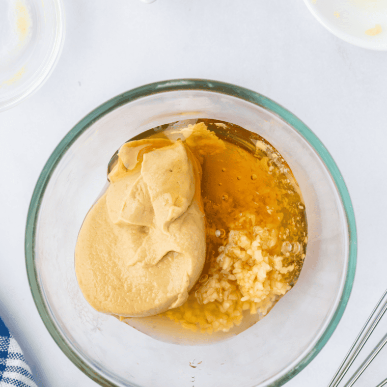 Honey Dijon sauce being whisked with mustard, honey, vinegar, and garlic.
