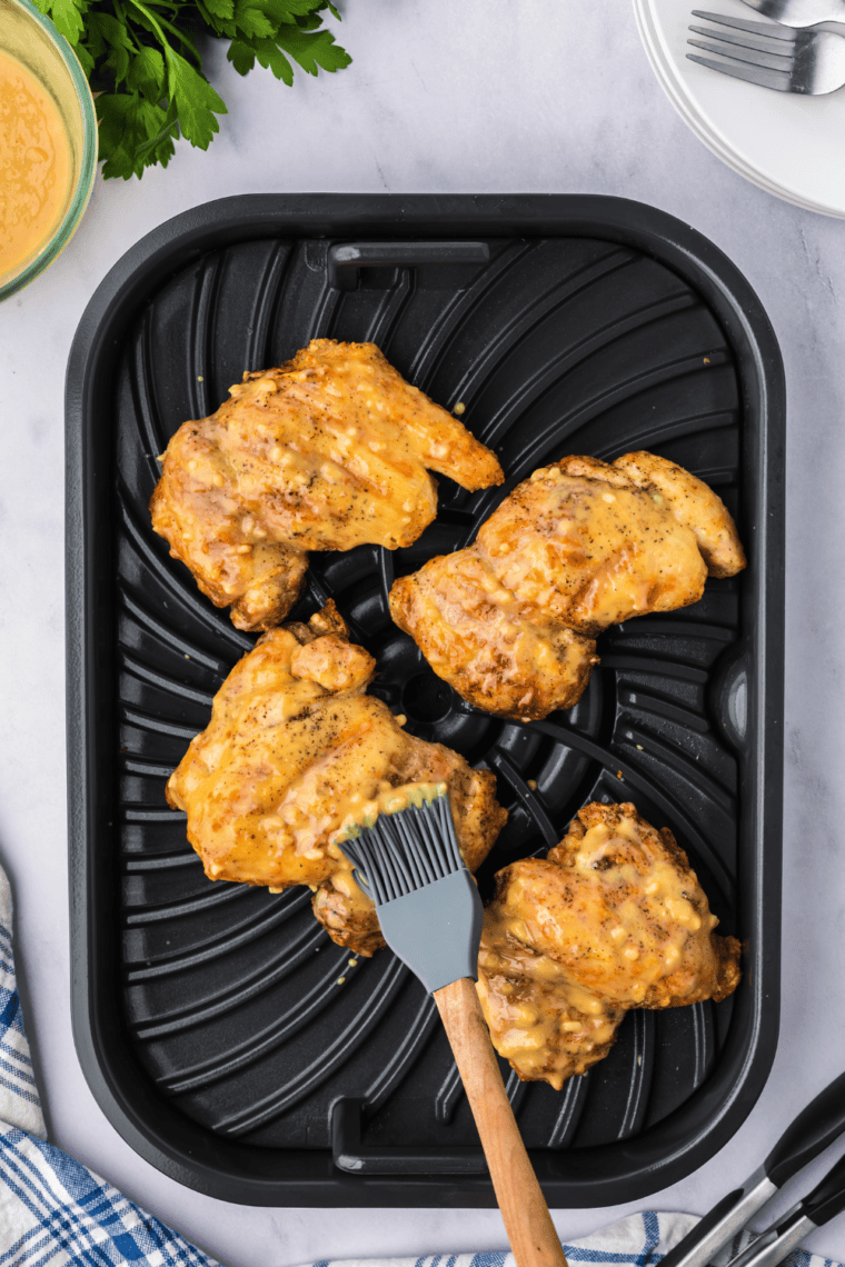 Grilled chicken thighs being brushed with honey Dijon sauce.