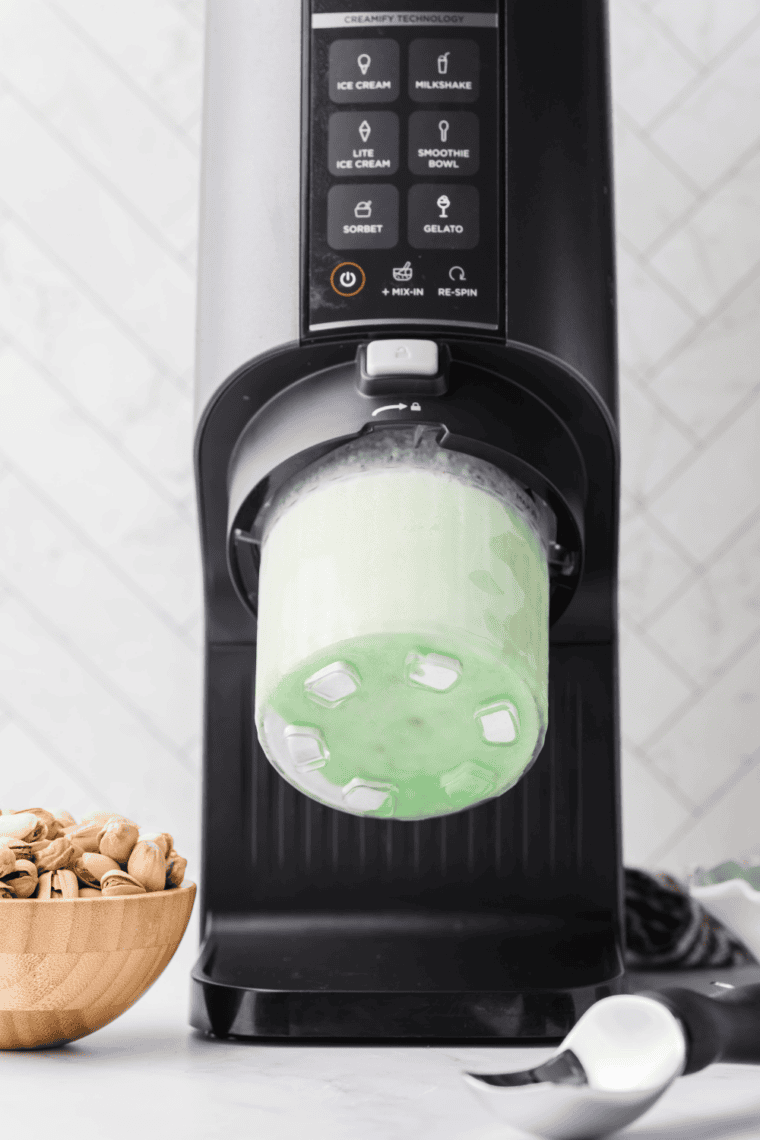 Frozen green ice cream pint locked into Ninja Creami machine for processing.