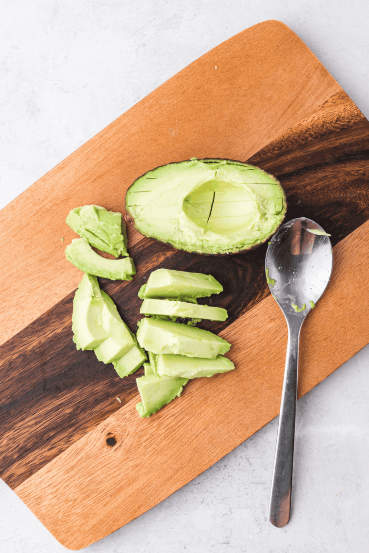bite-sized avocado cubes on cutting board being patted dry with paper towel