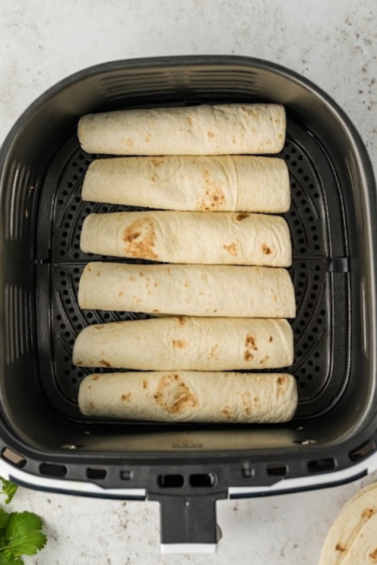 Hot dog taquitos rolled and placed seam-side down before air frying.