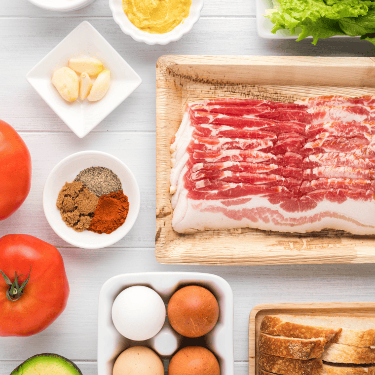 Ingredients needed for Bacon, Lettuce, Tomato, and Egg Sandwich Recipe on kitchen table.