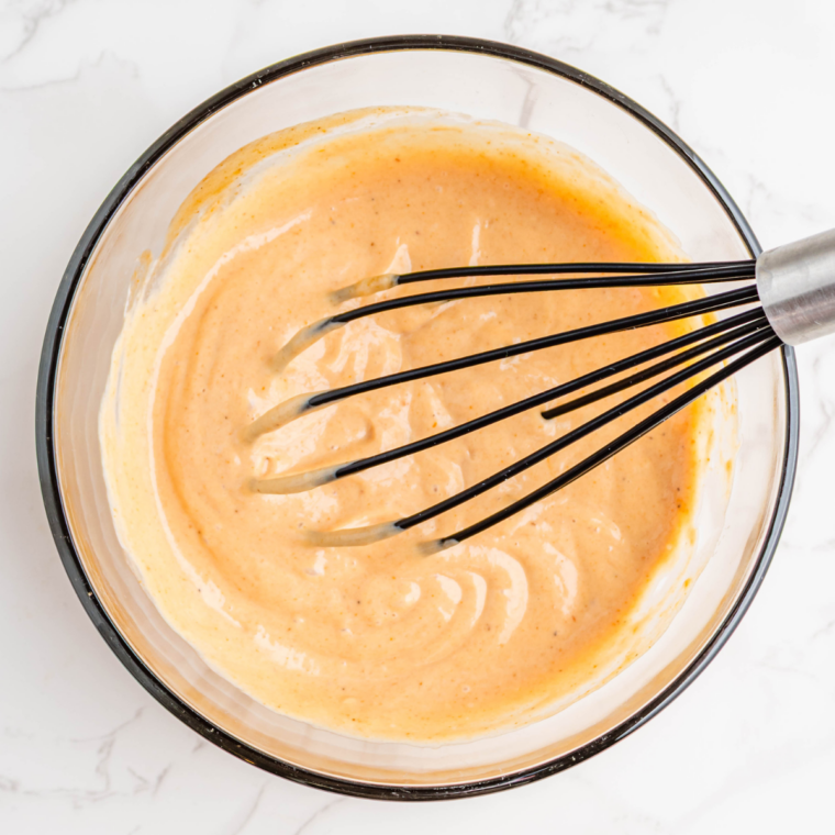 Small bowl of campfire sauce ingredients being mixed with creamy texture and spices blending together.