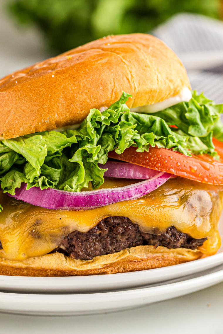 Fully assembled bacon smash burger stacked with sauce, lettuce, tomato, and pickles ready to eat.