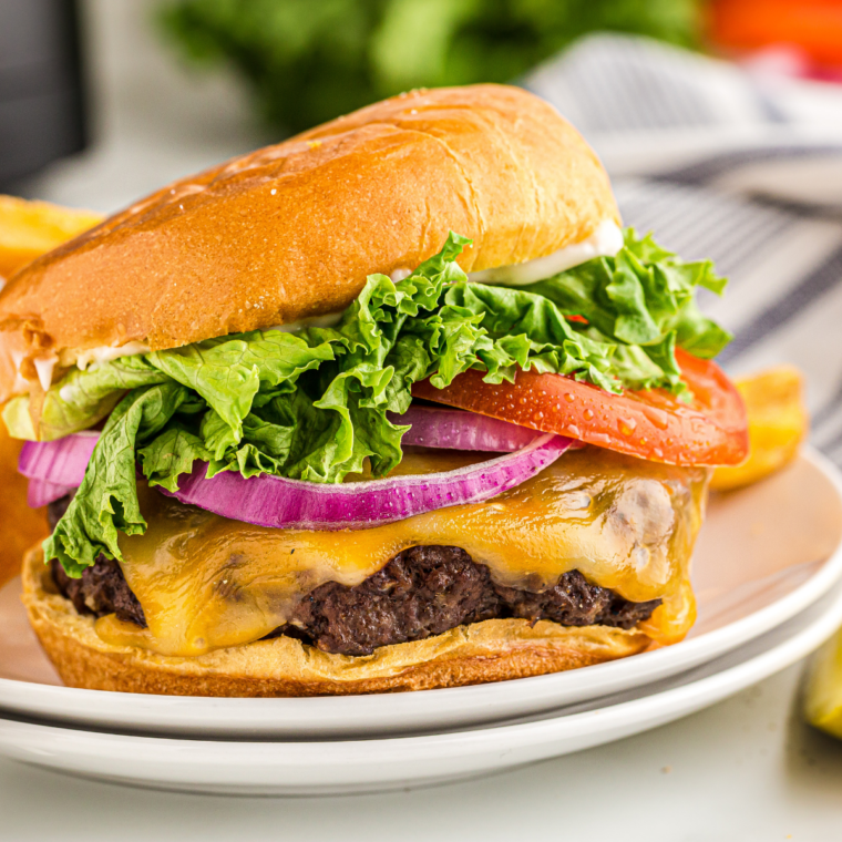 Close-up of campfire smash bacon cheeseburger with crispy beef edges, melted cheddar cheese, and bacon on a toasted brioche bun.