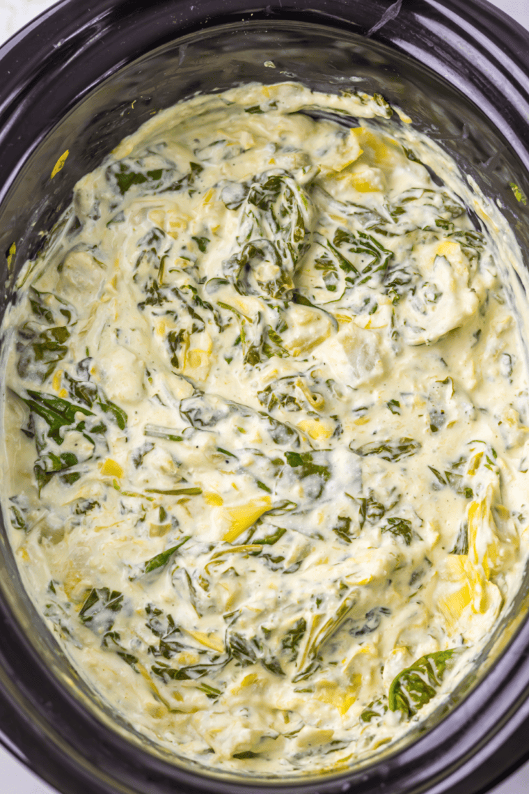 Hot spinach dip being stirred until smooth and creamy texture forms