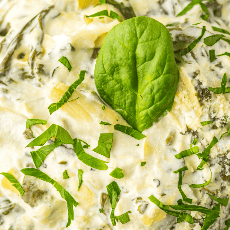 Warm and creamy Cheesecake Factory Spinach Dip served in a bowl with melted cheese and tortilla chips for dipping.