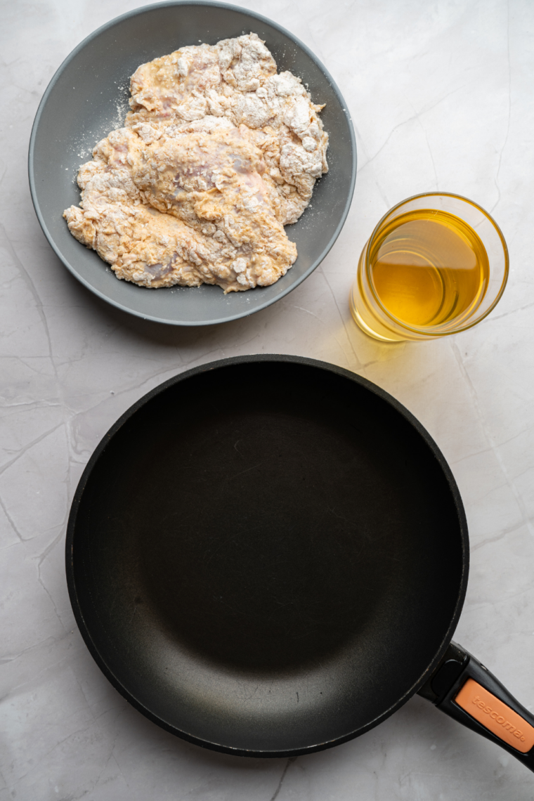 Shallow dish with seasoned flour mixture whisked together including spices, cornstarch, and baking powder for a light crispy chicken breading coating.