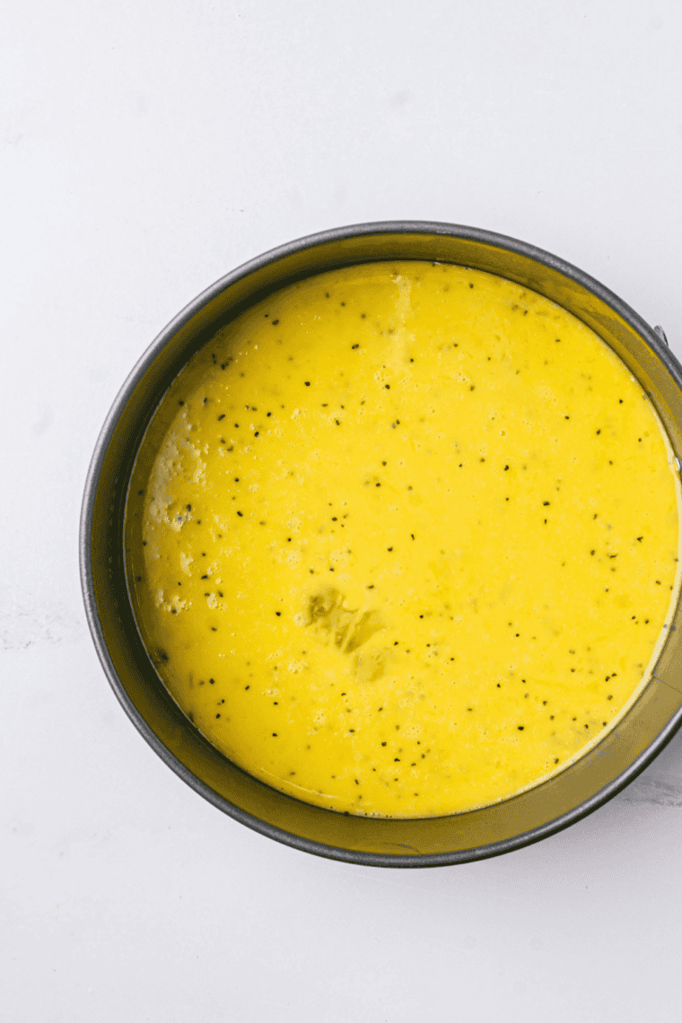 Whisked eggs mixed with bacon, ham, sausage, peppers, onions, mushrooms, and cheese in bowl