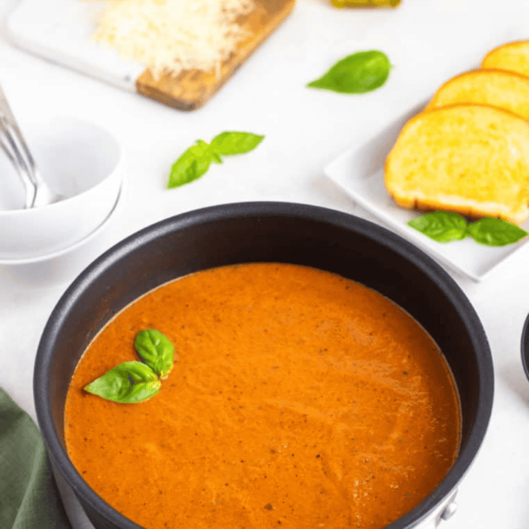 Serving the creamy tomato basil soup in bowls, garnished with fresh basil.