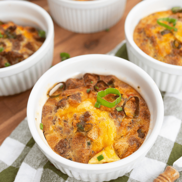 Golden baked breakfast strata casserole with layers of bread, eggs, cheese, sausage, and vegetables in a baking dish, fresh from the oven.