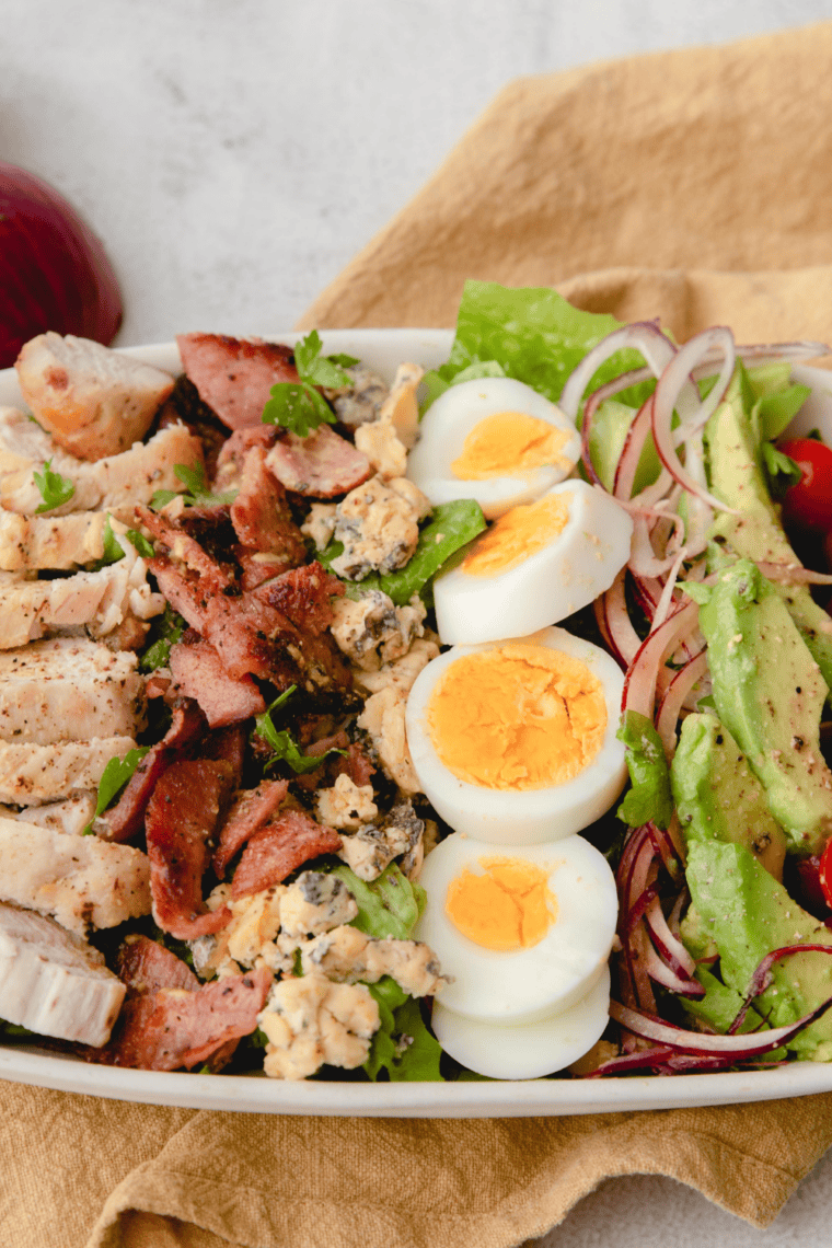 Fresh Cobb salad with romaine lettuce, grilled chicken, crispy bacon, hard-boiled eggs, avocado, cherry tomatoes, and creamy dressing inspired by First Watch.