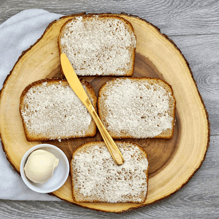 Slices of sourdough bread with butter spread on one side for grilling