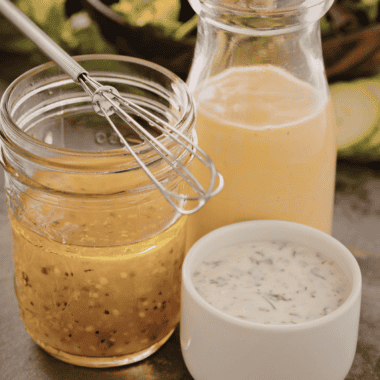 Creamy homemade lemon dressing in a glass jar with fresh lemon juice, olive oil, and herbs, served alongside a fresh green salad.