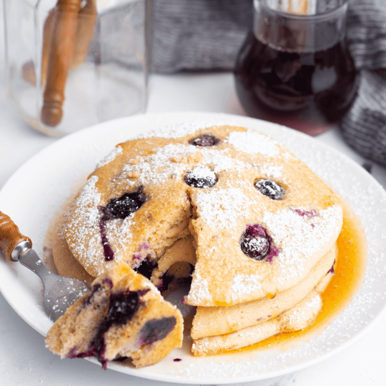 Serving lemon ricotta pancakes with berries, powdered sugar, and syrup