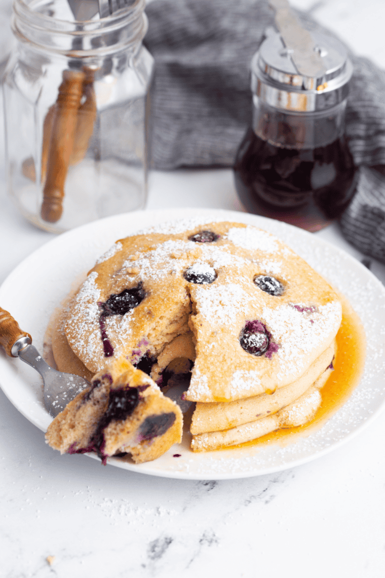 Fluffy lemon ricotta pancakes stacked and topped with powdered sugar, fresh berries, and syrup for a bright brunch-style breakfast.