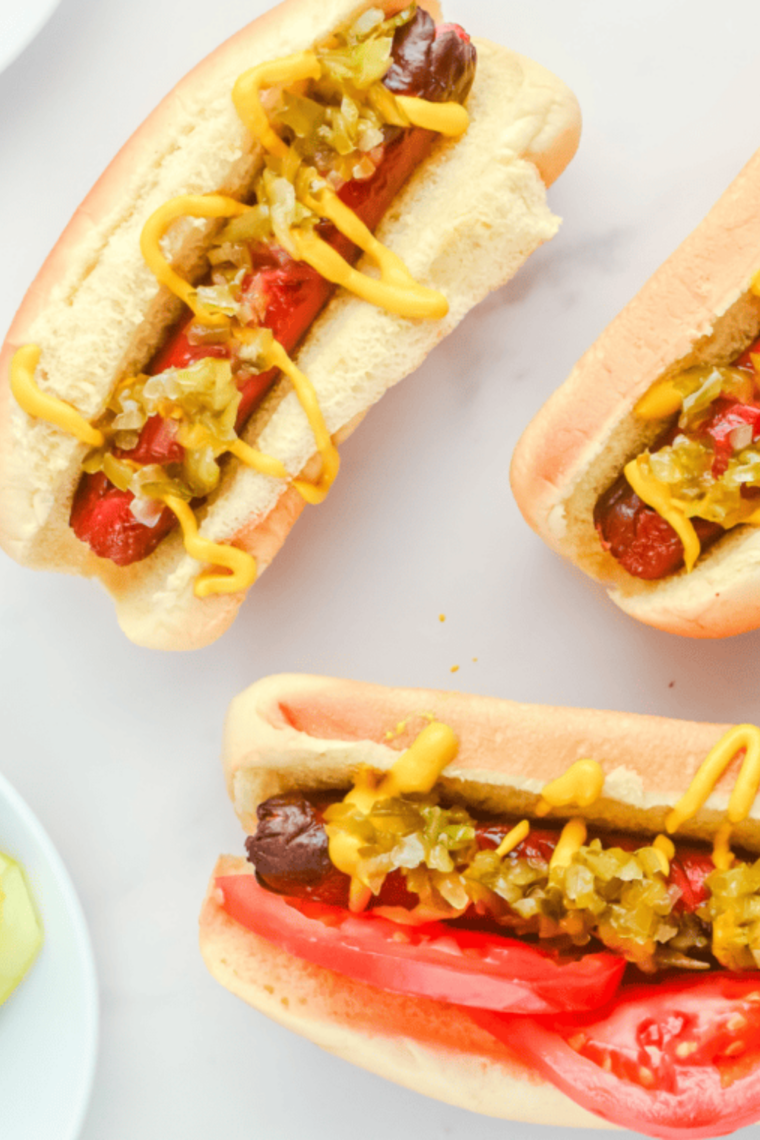 Hot dogs cooking inside an Instant Pot with steam rising, fully heated and ready to serve in buns.