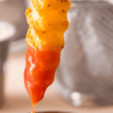 Bowl of homemade Lawry&rsquo;s French fry seasoning spice mix sprinkled over crispy golden fries on a rustic surface.