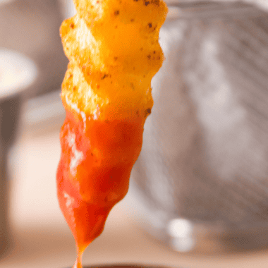 Bowl of homemade Lawry&rsquo;s French fry seasoning spice mix sprinkled over crispy golden fries on a rustic surface.