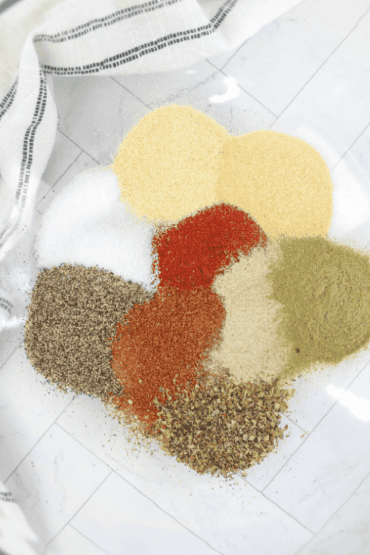 Adding dried onions, spices, and bouillon powder to a mixing bowl