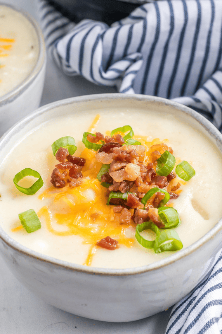 Bowl of creamy McAlister&rsquo;s potato soup topped with crispy bacon, shredded cheddar cheese, and green onions rich copycat loaded baked potato soup.