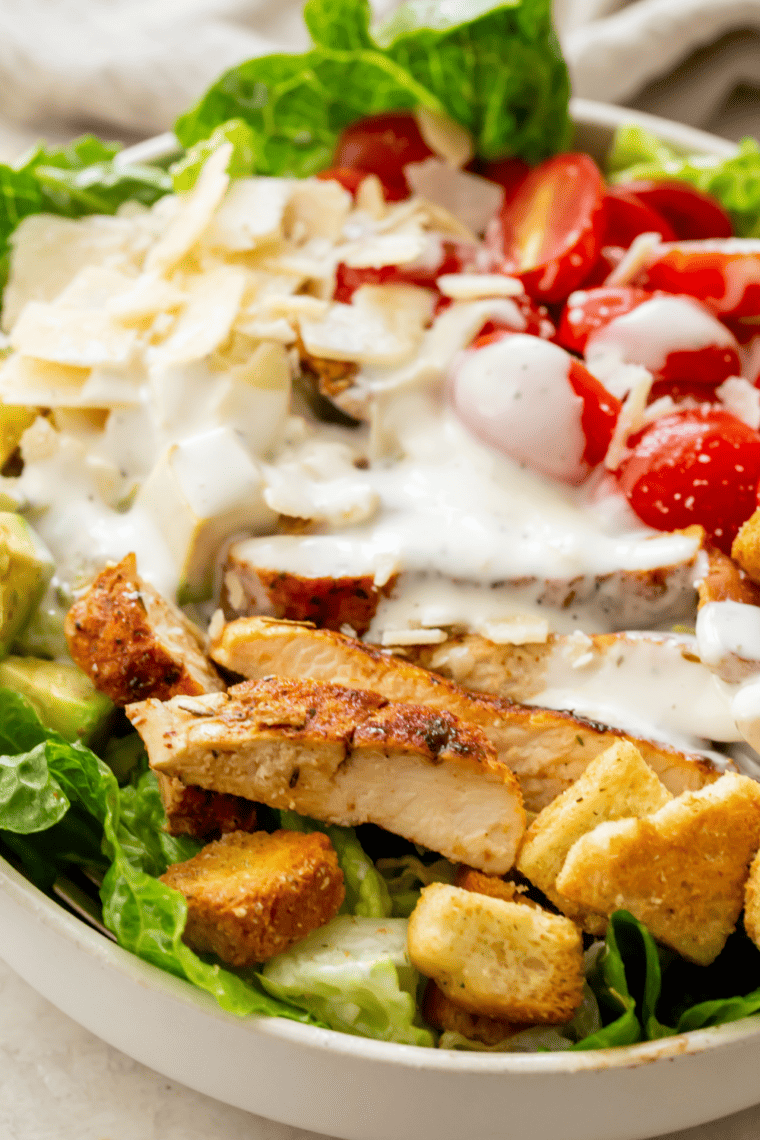 Homemade Red Robin style ranch dressing in a bowl with fresh herbs, served with fries, vegetables, and chicken wings for dipping