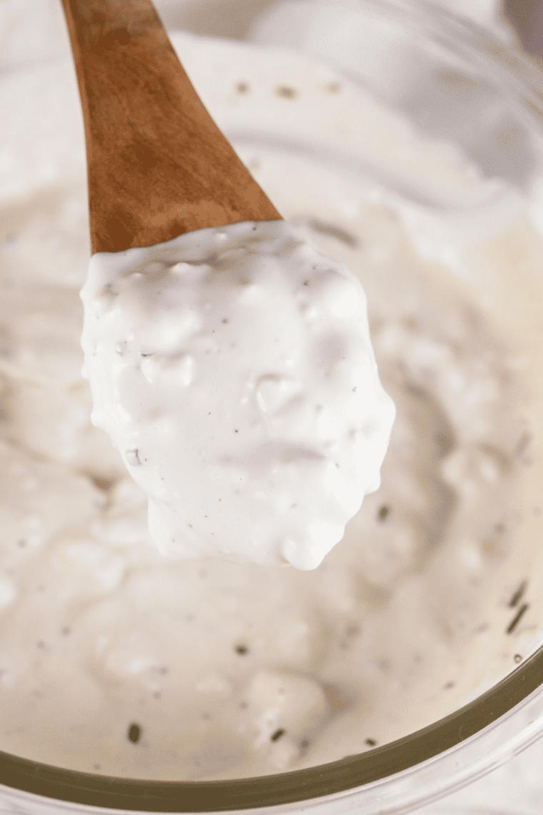Whisking mayonnaise, sour cream, and buttermilk in a bowl until smooth and creamy.