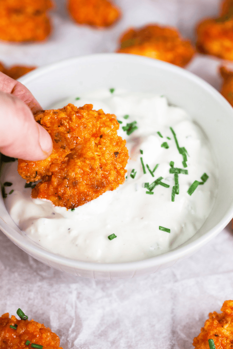 Close-up of homemade ranch dressing with herbs in a bowl served with chicken wings and fresh veggies for dipping