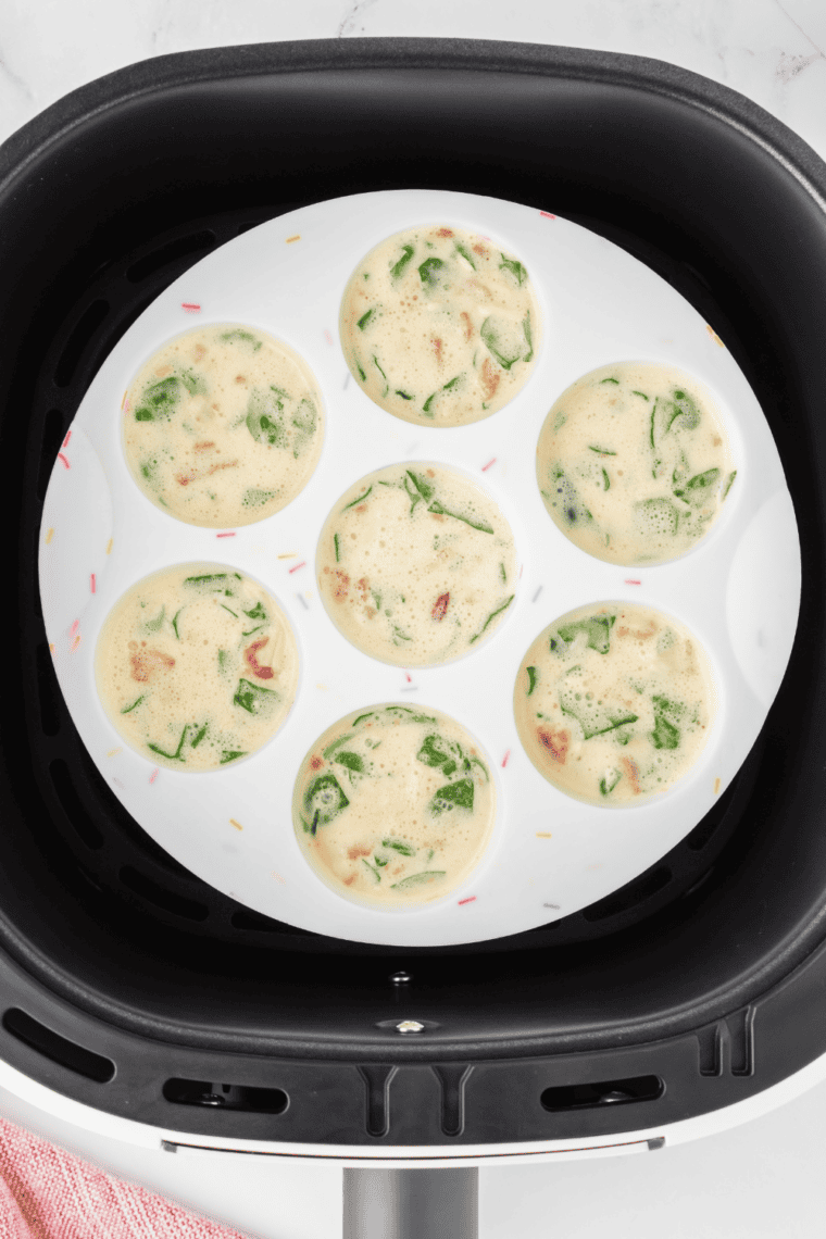 Pouring egg mixture into muffin tin cups evenly, filling each about three-quarters full.