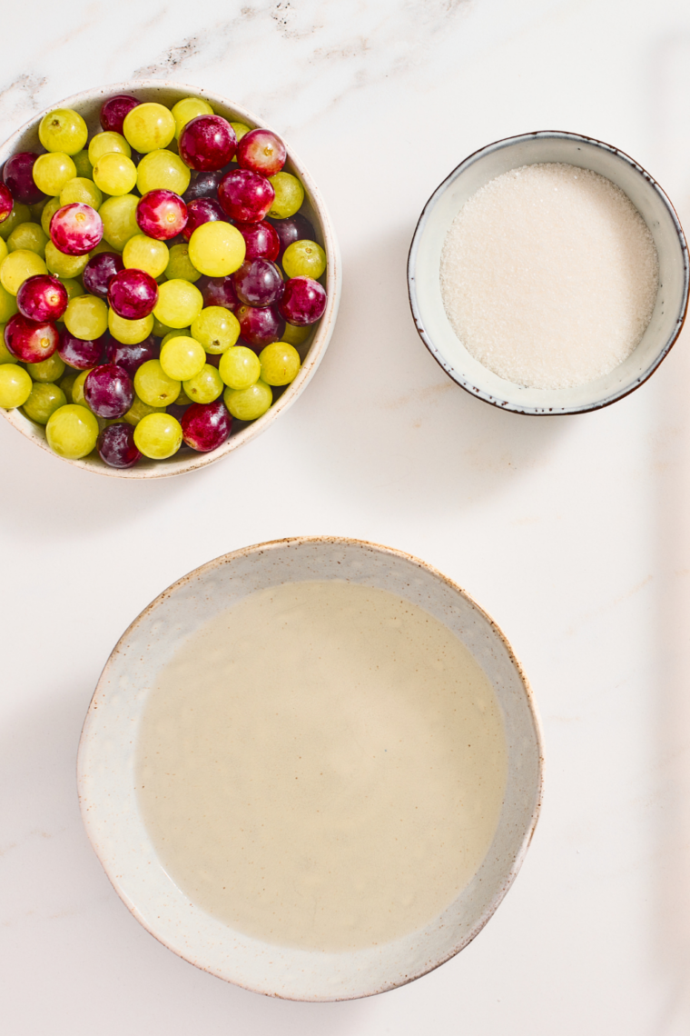 Fresh grapes being dipped into warm simple syrup and coated evenly