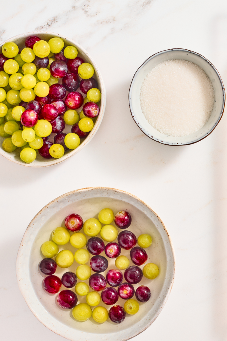 Sugar syrup coated grapes draining on a wire rack over a baking sheet