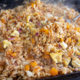 Fried rice cooking on Blackstone griddle with spatula