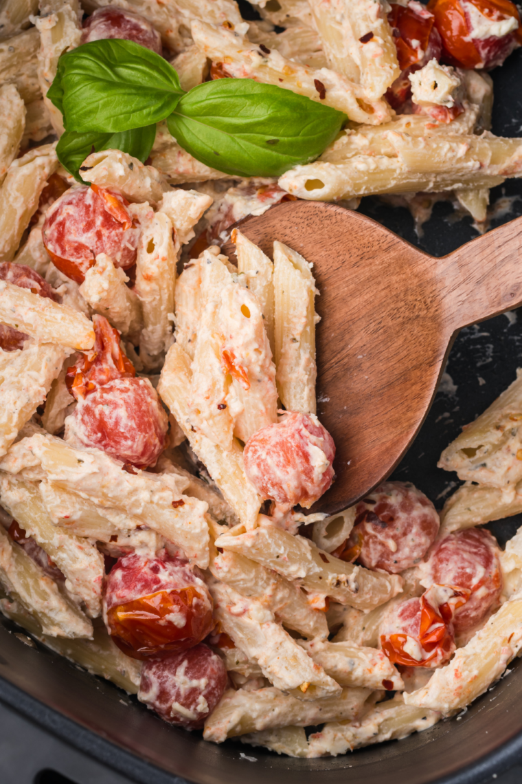 checking air fryer Boursin pasta as tomatoes burst and sauce forms