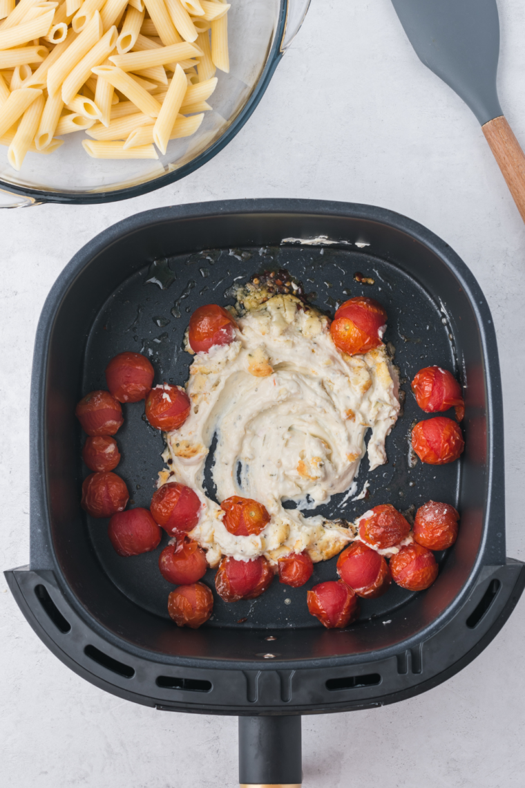 cherry tomatoes and Boursin cheese arranged in air fryer before cooking
