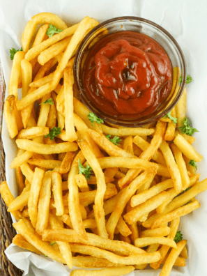 Bowl of homemade Zaxby&rsquo;s fry seasoning spice mix sprinkled over crispy golden fries on a rustic table.