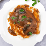 Slow cooker pork chops smothered in creamy mushroom and French onion sauce on a serving plate.