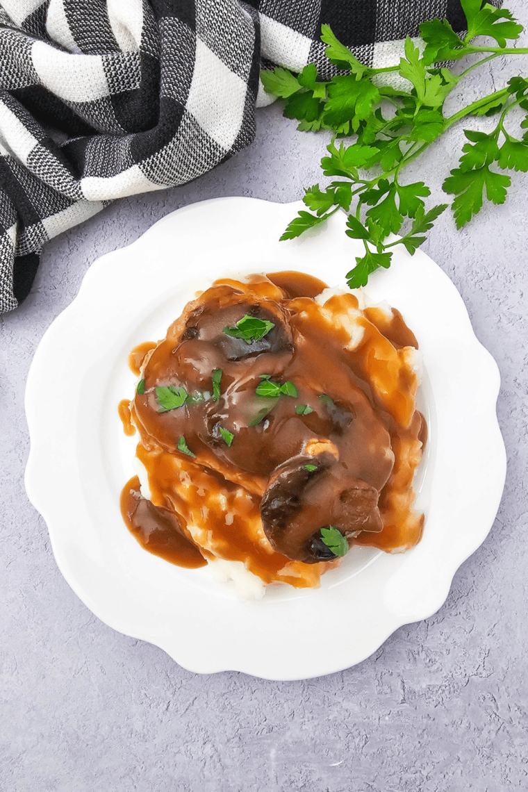 Tender slow cooker pork chops on a plate topped with French onion mushroom gravy