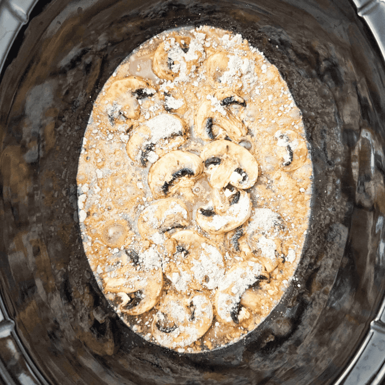 Cream of mushroom soup being poured from the can over pork chops and French onion soup mix in the slow cooker.