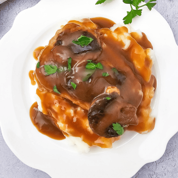 Slow cooker pork chops smothered in creamy mushroom and French onion sauce on a serving plate.