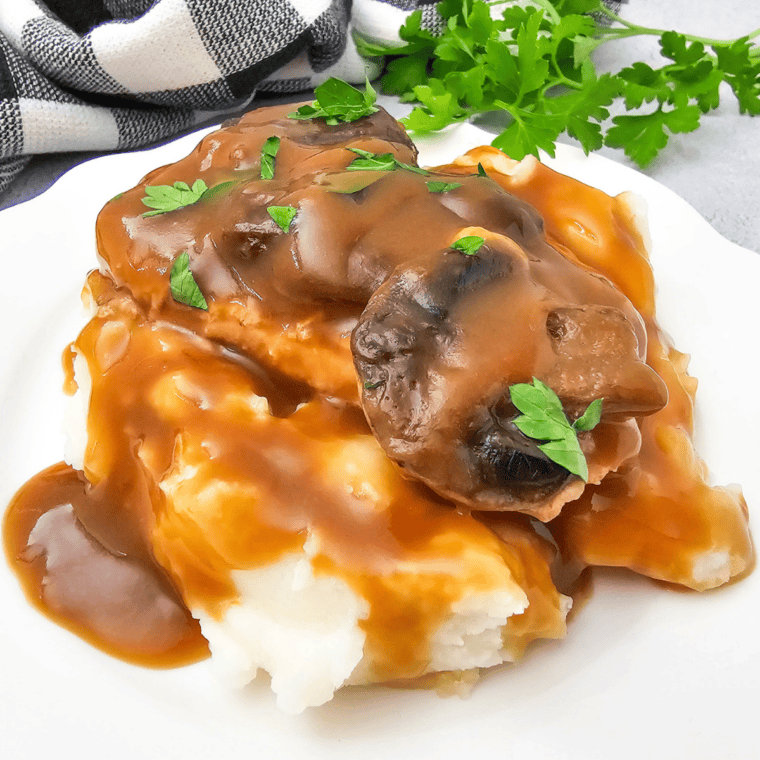 Tender crock pot pork chops coated in a rich, creamy sauce served on a dinner plate.