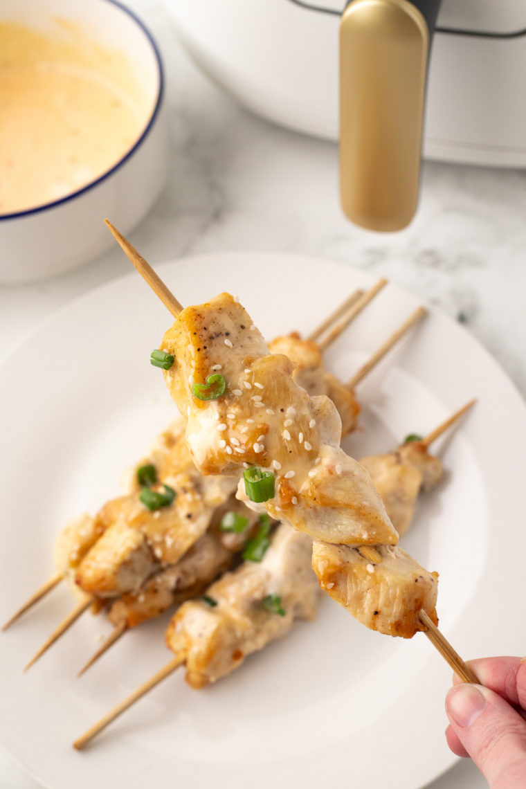 Chicken skewers cooking evenly in air fryer with caramelized sauce edges