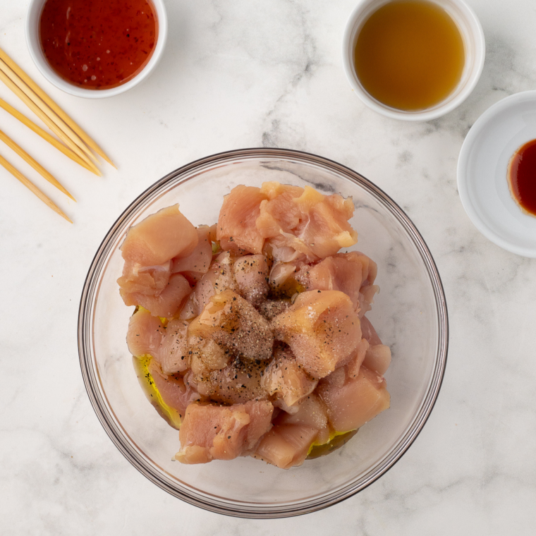 Chicken cubes tossed with oil and spices in large mixing bowl