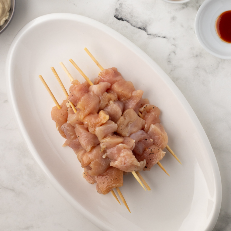 Chicken pieces threaded evenly onto skewers with spacing between cubes