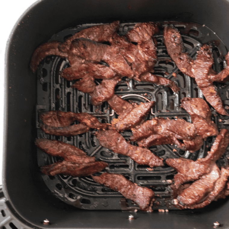 Marinated bulgogi beef in a single layer in the air fryer basket, caramelized at the edges