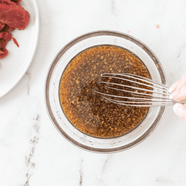 Soy sauce, brown sugar, sesame oil, garlic, and ginger whisked together in a bowl for bulgogi marinade