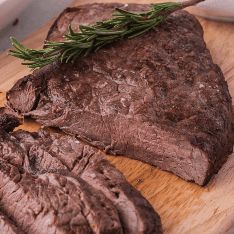 Air fryer round steak with a golden crust and tender pink center served on a plate.